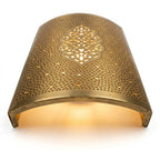 Angled view of a curved brass wall sconce with a central arabesque medallion