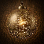Close-up of the dotted perforations on an illuminated Starfield brass globe pendant