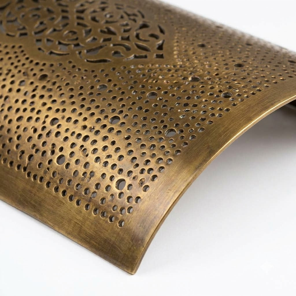 Close-up of the curved brass surface and tiny perforations of an arabesque wall sconce