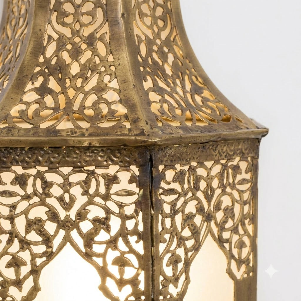Close-up of floral brass cutouts and panel seams on an arched lantern wall sconce