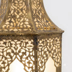 Close-up of floral brass cutouts and panel seams on an arched lantern wall sconce