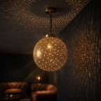 Starfield brass globe pendant projecting fine points of light onto dark walls