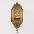 Angled view of a tall Moroccan brass wall lantern with faceted panels and a pointed finial