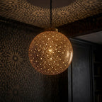 Starfield brass globe pendant casting dotted light patterns onto a dark ceiling